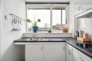 a white kitchen with a sink and a window at Cozy Stay Rotterdam City in Rotterdam