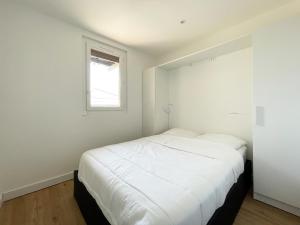 a bedroom with a white bed and a window at Au pied des dunes in Seignosse