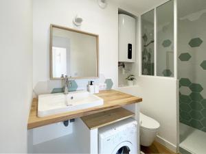 a bathroom with a sink and a washing machine at Au pied des dunes in Seignosse