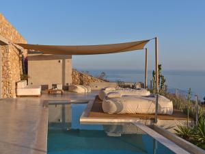 a villa with a swimming pool with beds and a canopy at Santorini Heights in Pyrgos
