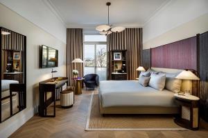 チューリッヒにあるスモール ラグジュアリー ホテル アンバサダー チューリッヒのベッドとデスクが備わるホテルルームです。