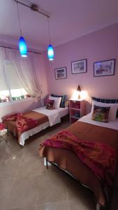 two beds in a room with purple walls and blue lights at Chez Axia Tanger in Tangier
