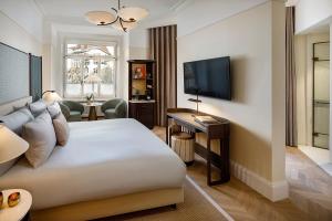 um quarto de hotel com uma cama e uma televisão em Small Luxury Hotel Ambassador Zurich em Zürich