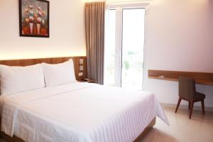 Surabaya River View Hotel في سورابايا: غرفه فندقيه سرير ابيض ونافذه