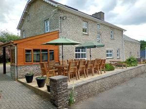 uma mesa e cadeiras com guarda-sóis em frente a um edifício em Dolau Farmhouse em Llanwnen