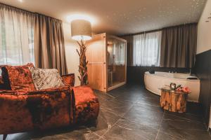 a living room with a tub and a couch and a chair at Hotel Pfeldererhof Alpine Lifestyle in Moso