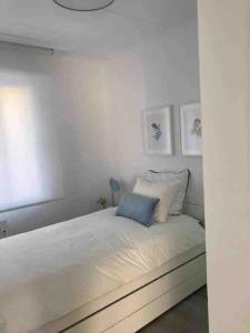 a white bedroom with a bed with a blue pillow at Casa dos Alén in Ourense