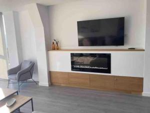 sala de estar con TV de pantalla plana en la pared en Casa dos Alén, en Ourense