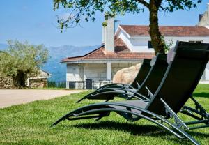 two chairs sitting in the grass in front of a house at Casa dos Alén in Ourense