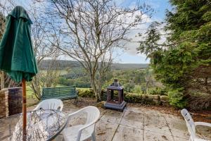 een patio met een tafel en stoelen en een groene parasol bij Family Country Cottage with a private Valley View in Scarborough