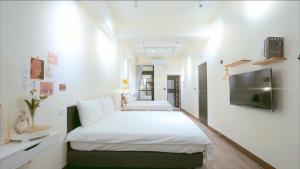 1 dormitorio con 2 camas y TV de pantalla plana en 咻咻宿 Xiuxiu 電梯宅 en Taitung