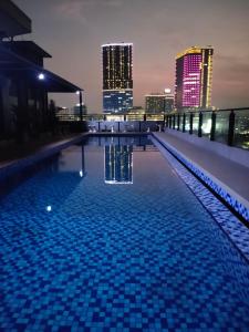 uma piscina com um horizonte da cidade à noite em Surabaya River View Hotel em Surabaia