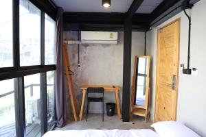 a room with a table and a chair and a window at The Cube Hostel Khaosan in Bangkok