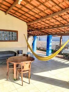 a hammock on a patio with a table and chairs at Casa Rústica em Morro Branco - na quadra da praia in #N/A