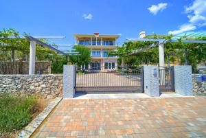 a house with a gate and a stone wall at Apartments ROYAL in Kornić