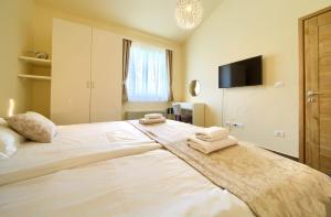 a bedroom with a large white bed with towels on it at Apartments ROYAL in Kornić