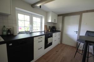 a kitchen with white cabinets and a black counter top at Hus Boompecker in Achtrup