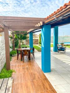 a patio with a wooden table and blue columns at Casa Rústica em Morro Branco - na quadra da praia in #N/A