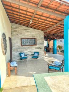 a patio with blue chairs and a stone wall at Casa Rústica em Morro Branco - na quadra da praia in #N/A