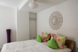 a bedroom with a bed with green and pink pillows at Schönes Studio in der Altstadt von Meersburg in Meersburg +3 photos