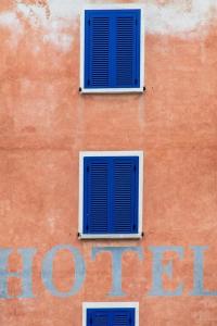 un edificio con dos ventanas azules. en Hôtel Restaurant le Bellevue, en Propriano