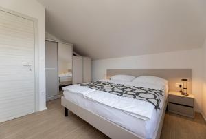 1 Schlafzimmer mit einem großen weißen Bett und einem Badezimmer in der Unterkunft Apartments Crneković III in Baška