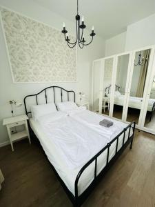 a bedroom with a bed with white sheets and a chandelier at Pistacjowy - Apartamenty Smart Projekt in Tarnów