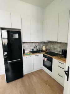cocina con armarios blancos y nevera negra en Pistacjowy - Apartamenty Smart Projekt, en Tarnów