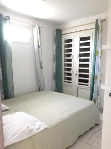 a bedroom with a white bed and a window at Appartement de 2 chambres avec jardin amenage et wifi a Le Lamentin a 4 km de la plage in Le Lamentin