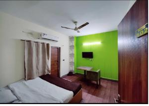 Habitación con una pared verde, cama y escritorio. en Hotel TSR By WB Inn en Agra
