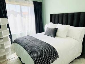 a bed with a black headboard and white pillows at Cozy Self Catering Apartment with Golf Course Views, Jackal Creek Golf Estate in Roodepoort