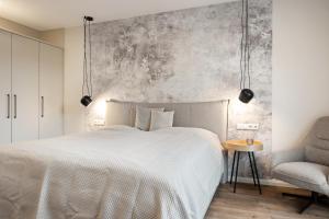 een slaapkamer met een wit bed en een stoel bij My Suite Leesch - Hotel & Restaurant nahe Büsum - Hunde herzlich willkommen in Reinsbüttel