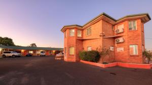a brick building with a parking lot in front of it at Across Country Motor Inn in Dubbo