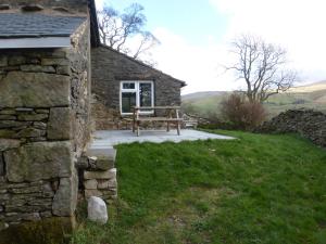 una casa de piedra con un banco delante en Sally End en Ravenstonedale