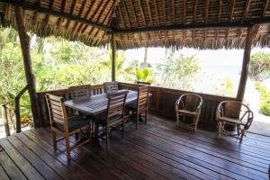 una terraza de madera con mesa y sillas. en Baobab Beach Villa, Ushongo Beach, Pangani en Ushongo Mabaoni