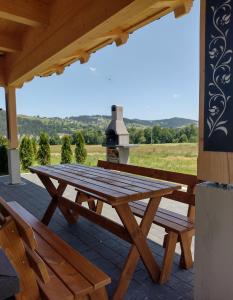 una mesa de picnic de madera y 2 bancos en un patio en Na Południe en Białka Tatrzanska