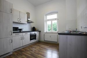 uma cozinha com armários brancos e piso em madeira em Holiday flat Askani Ballenstedt - DMG03102h-EYC em Ballenstedt