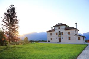 un grand bâtiment blanc sur un champ herbeux avec le coucher du soleil dans l'établissement Villa D'Or, à Mel