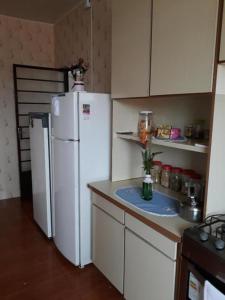 a kitchen with a white refrigerator and a counter at Pousada Irmãs Franciscanas in Lages