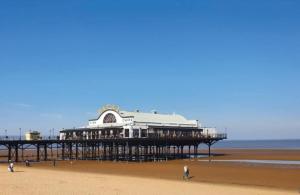 um cais na praia com pessoas andando na areia em Fabulous Modern Holiday Home BEACH Cleethorpes Beach Thorpe Park Haven em Cleethorpes