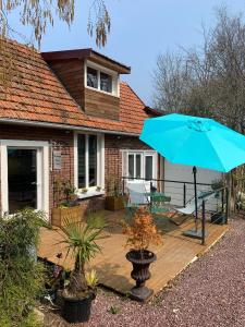 um pátio com um guarda-chuva azul e uma casa em Le Pré Aux Loups em Hautot-sur-Mer