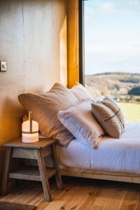 a bed with pillows and a table next to a window at White House Hideaway in Brockhampton