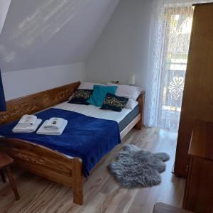 a bedroom with a bed with a blue blanket and a window at Tu i Teraz - pokoje in Bukowina Tatrzańska
