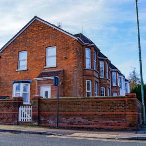 una casa de ladrillo con una valla de ladrillo delante de ella en Bedford Rd Apartment Ideal for Hospital & Town Centre en Kempston