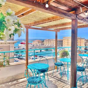 een patio met tafels en stoelen en uitzicht op het water bij Hotel Posta in Siracusa