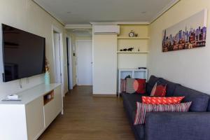 sala de estar con sofá azul y TV de pantalla plana en Sun&Beach View Apartments, en Benidorm