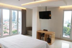 pokój hotelowy z łóżkiem i telewizorem z płaskim ekranem w obiekcie Surabaya River View Hotel w mieście Surabaja