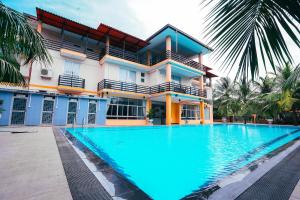 a house with a swimming pool in front of a building at Sun Ray Rest House in Kalkudah