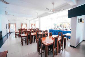 comedor con mesas y sillas de madera en Sun Ray Rest House, en Kalkudah