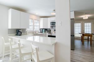 a white kitchen with white cabinets and white chairs at House in Mobile Newly Renovated! Quiet & Centrally Located! in Mobile